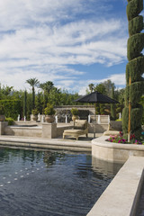 Topiary in garden with poolside sunlounger against cloudy sky