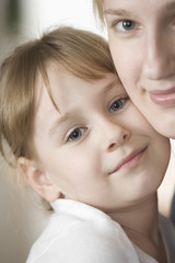 Closeup portrait of cute girl and mother smiling together at home