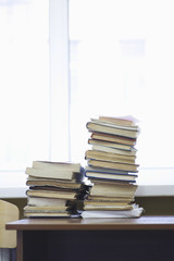 Books stacked on wooden desk in library