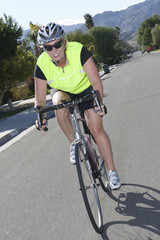 Confident female cyclist in sportswear riding bicycle on street