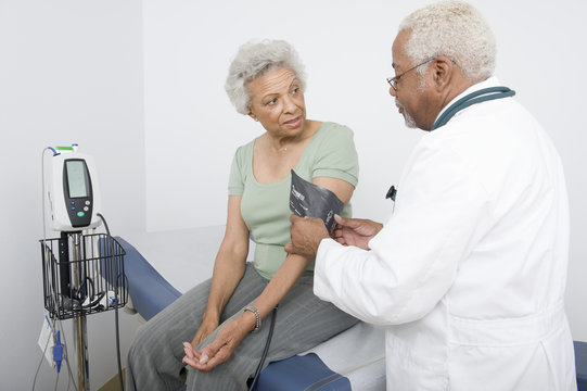 An African American male doctor measuring patient's blood pressure at clinic
