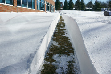 Obraz premium walking path beside building with snow removal after blizzard