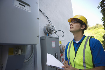 Maintenance worker reading meter of solar generation unit in Los Angeles, California
