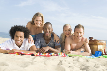 Group portrait of multiethnic young people lying on sand at beach