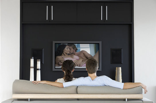 Back View Of Couple Watching Romantic Movie On Television In Living Room