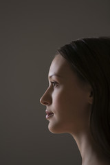 Closeup side view of beautiful young woman over black background