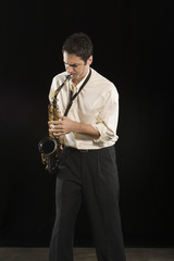 Fototapeta na wymiar Caucasian man blowing saxophone isolated over black background