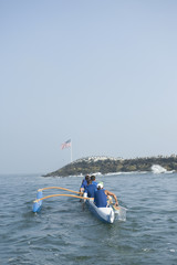 Rear view of multiethnic outrigger canoeing team on water