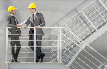 Full length of young male architect discussing on stairway