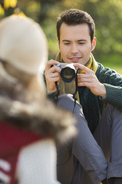Young man photographing woman in park
