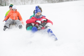 Young couples enjoying sled ride on snow covered slope