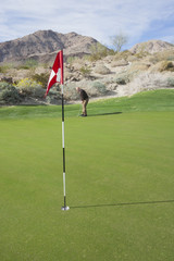 Obraz premium Senior man playing golf with flag in foreground
