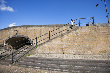 Side view of young woman walking down stairs against blue sky