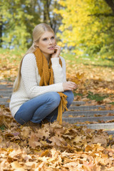 Full length of thoughtful young woman crouching on steps in park