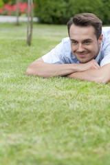 Happy young man lying on grass in park