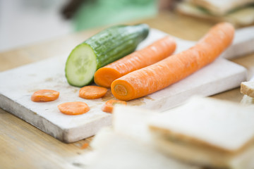 Carrots and cucumber on cutting board in kitchen