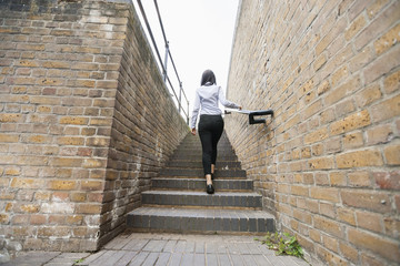 Rear view of young businesswoman walking up stairs