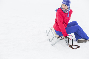 Fototapeta na wymiar Beautiful young woman sitting on sled