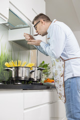 Mid-adult man tasting food while cooking in kitchen