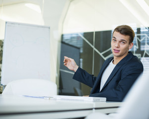Portrait of young businessman giving presentation at conference table