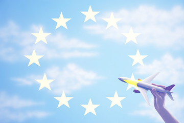 Person holding a toy plane flying in from of EU Flag