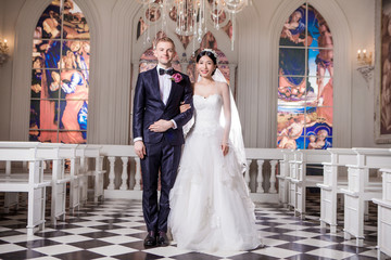 Portrait of confident wedding couple standing arm in arm at church