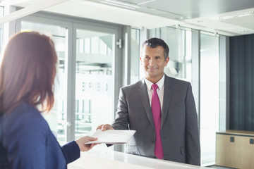 Businessman receiving document from receptionist in office