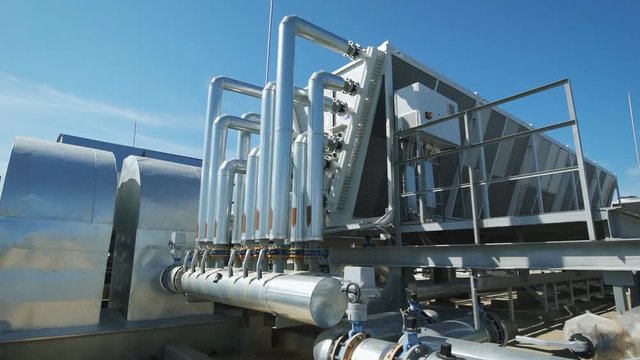 Metal chrome pipes are connected to a common water supply system for the enterprise. On the roof of an industrial building organized piping and ventilation.