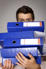 Young caucasian businessman holding a stack of binders