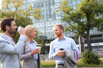 Businesspeople with disposable cups conversing in city
