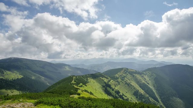 Beautiful white clouds in sky flying over green landscape in mountains time lapse