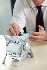 Businessman searching business card from stand
