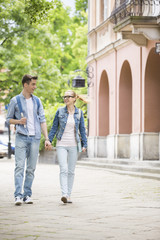 Fototapeta na wymiar Full length of young college couple talking while walking in campus
