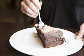 Close-up of woman's hand cutting chocolate pastry