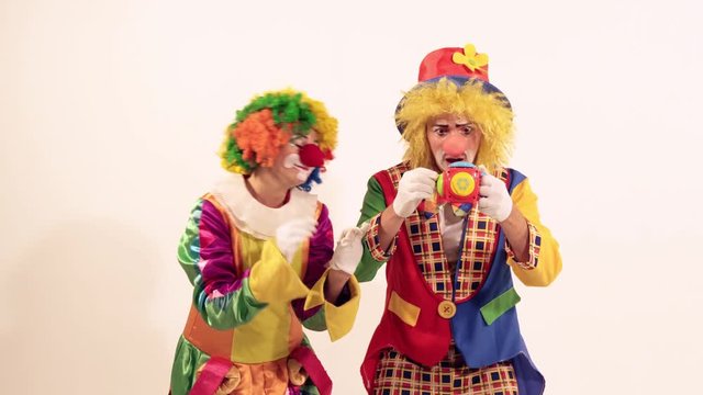 A couple of glad funny clowns playing and singing, when the toy frightens them