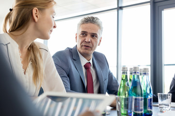 Mature businessman discussing with female colleague in board room