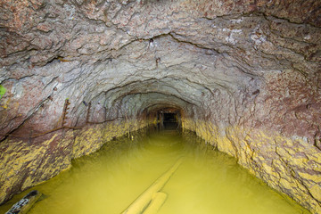 Abandoned old ore mine shaft tunnel passage flooded yellow water