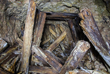 Abandoned old ore mine shaft tunnel passage with wooden barring