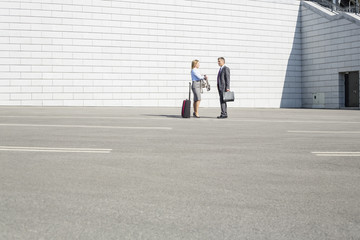 Businesspeople with luggage talking on street