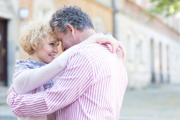 Obraz premium Happy middle-aged couple embracing in city