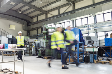 Blurred motion of business people wearing reflective clothing walking in metal industry