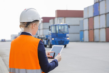 Rear view of female engineer using tablet PC in shipping yard