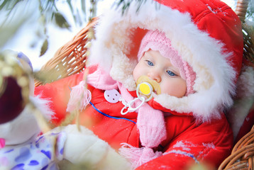 Little girl with a pacifier in his mouth is sitting in a sled an