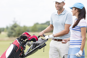 Naklejka premium Happy friends with bag talking at golf course