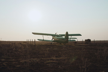 Fototapeta na wymiar old green airplane on the field a sunset background