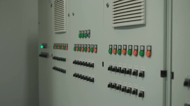 Large gray control panel with lots of buttons and switches. Camera smoothly move along the wall with electronic equipment on factory.