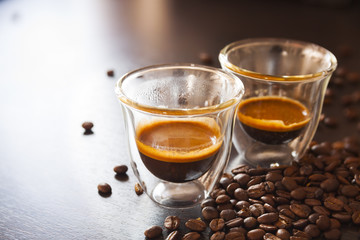 Two shot espresso in thermo glasses, brown background with coffee beans.