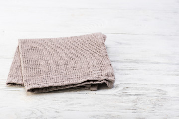 Gray napkin isolated on white wooden table. Copy space. Brick wall background. Front view.