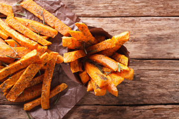 roasted sweet potatoes with herbs in a paper cone close-up. Horizontal top view