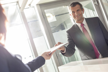 Businessman receiving document from receptionist in office